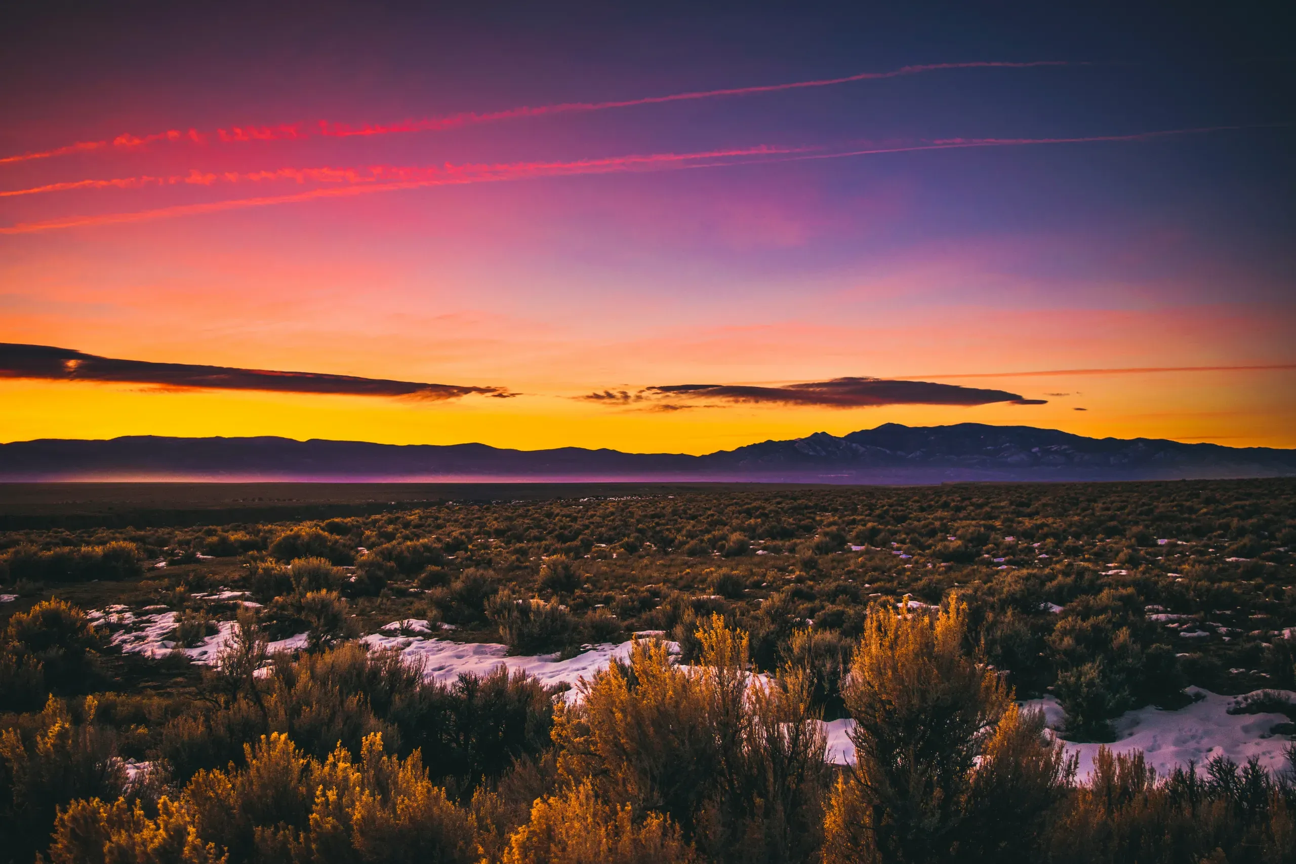 A stunning golden hour sunset full of hues of purple, red and orange- spanning across the desert landscape of New Mexico, USA