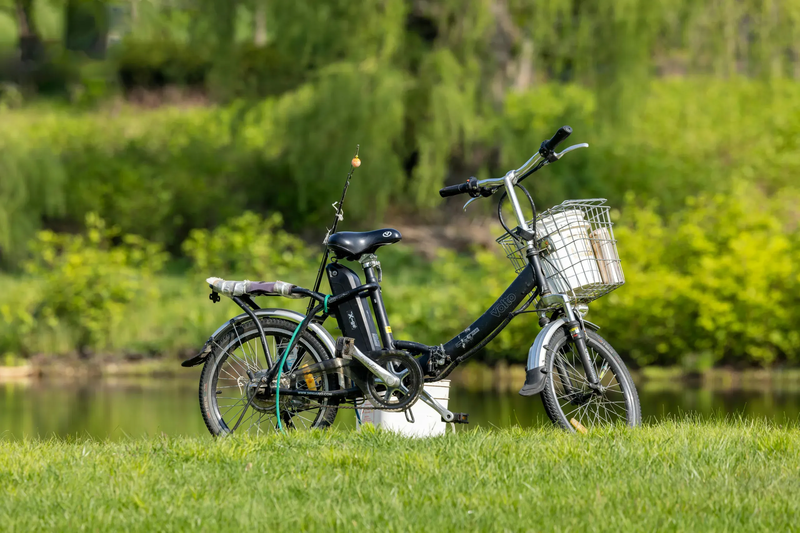 Southborough, Massachusetts. A bicycle and a fishing rod on a grass field by the river
