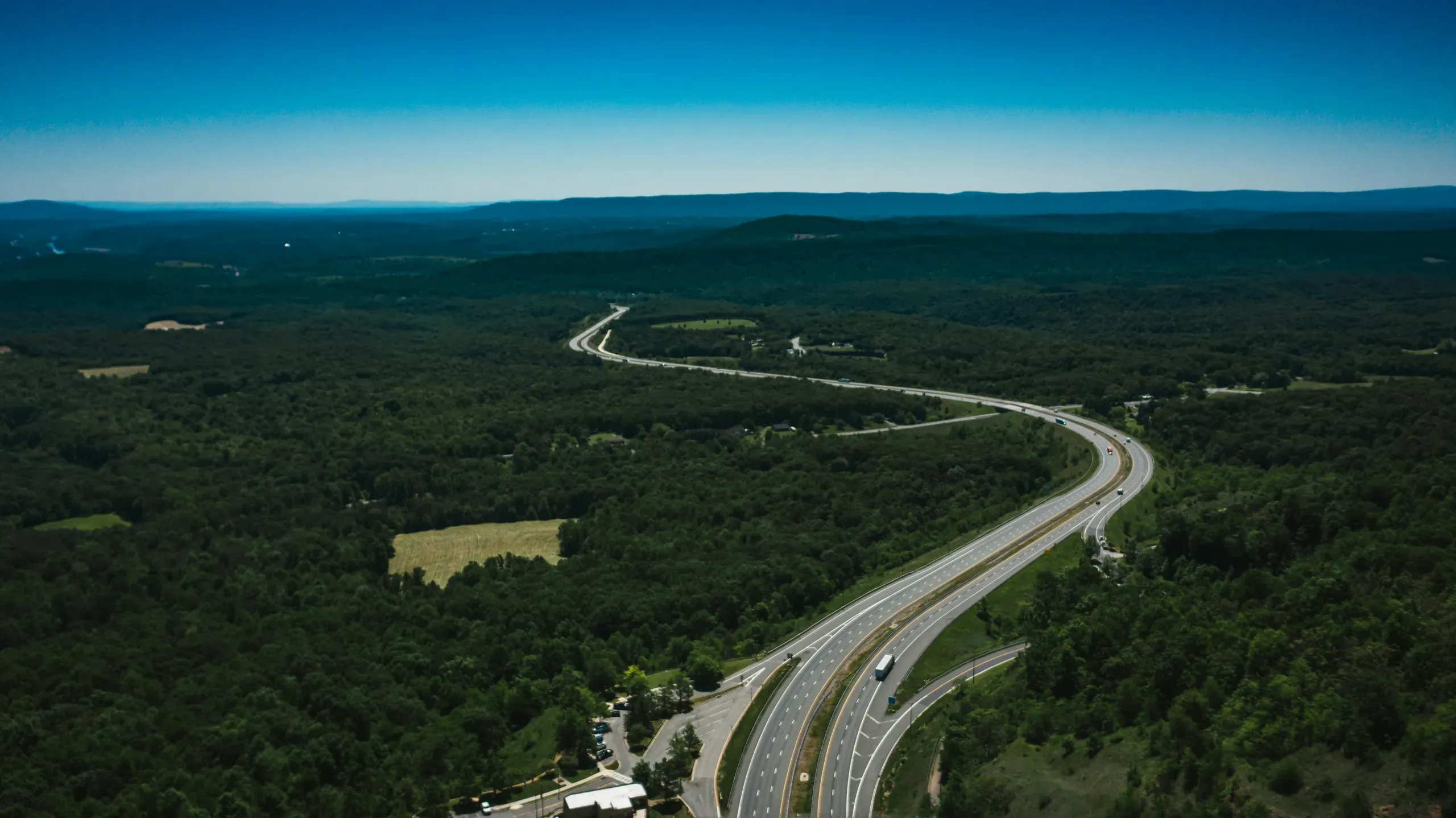 Hancock, Maryland. Wavy roadway between greenery forest under blue sky