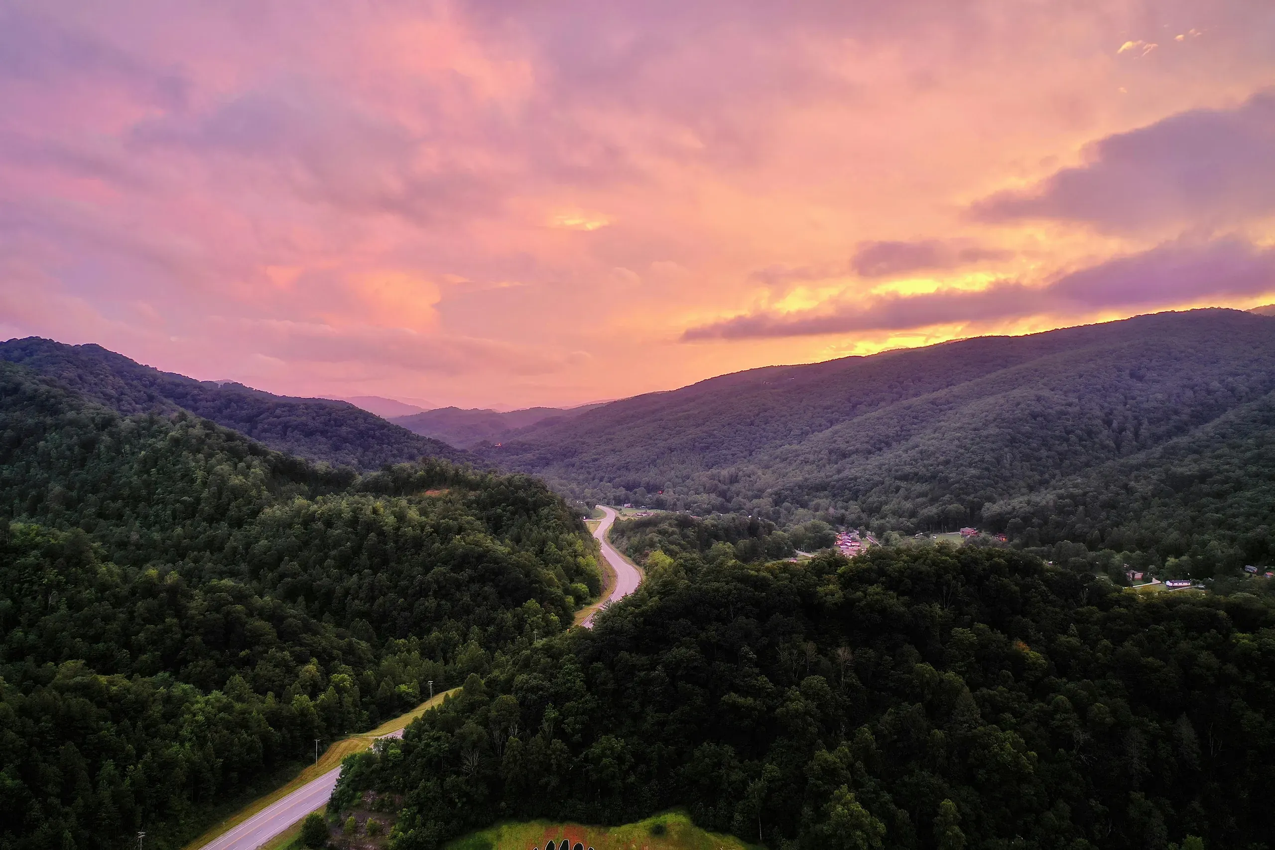 Harlan, Kentucky. Aerial photography of a road between the trees during sunset.