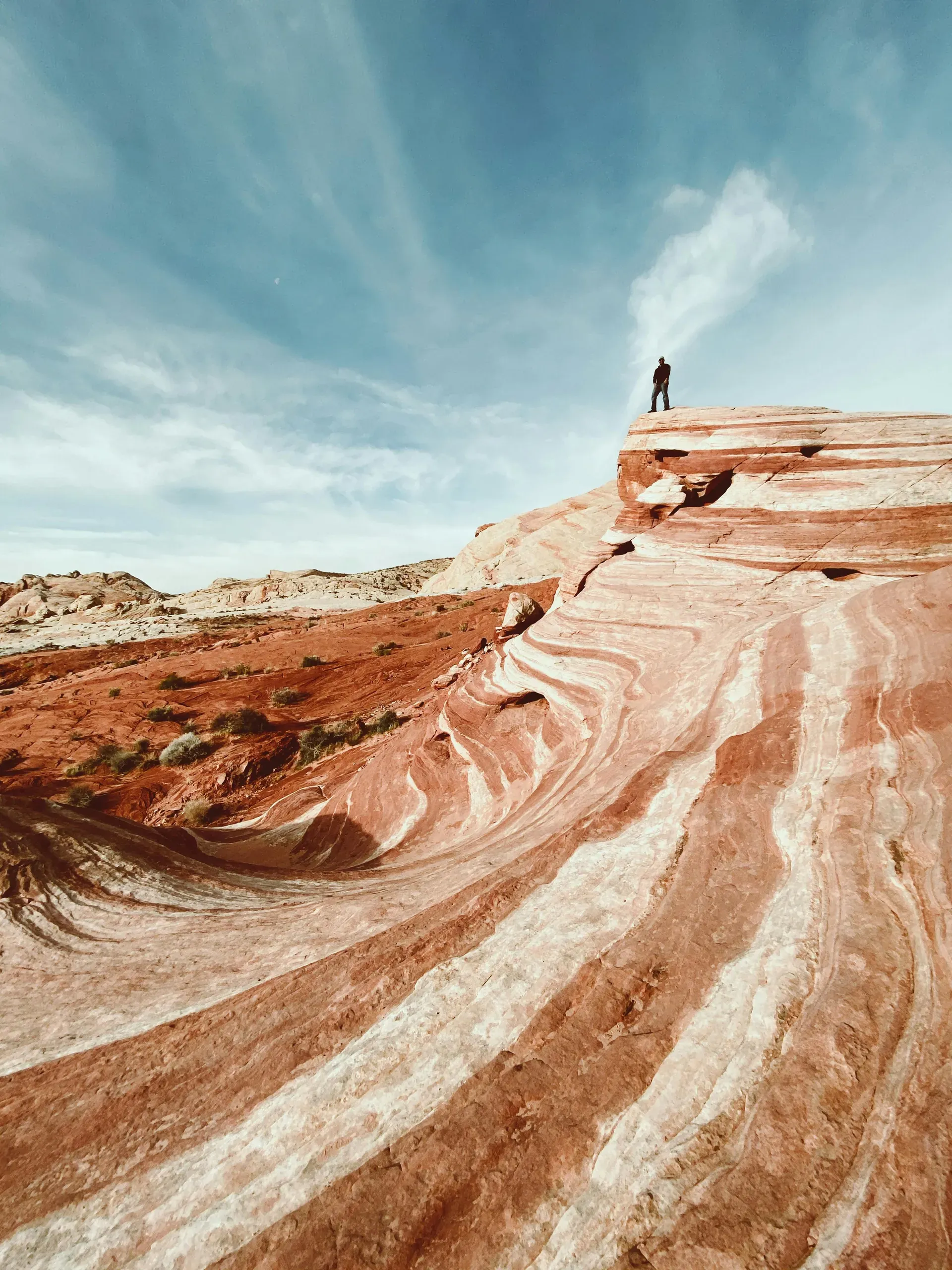 Clark County, Nevada. Person standing on brown rock formation under blue sky