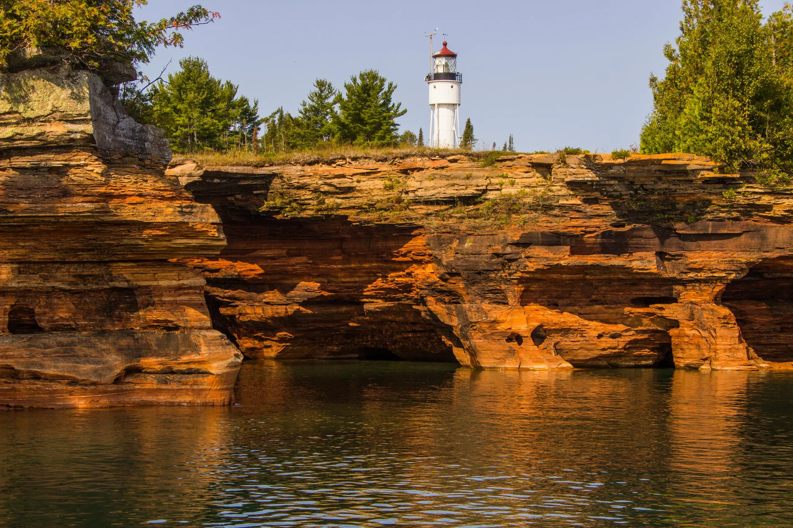 Apostle Islands, Wisconsin. A lighthouse sits on top of devils island of the Apostle Islands in Lake Superior. The island shores are lined with caves and pillars being eroded by the waves and storms.