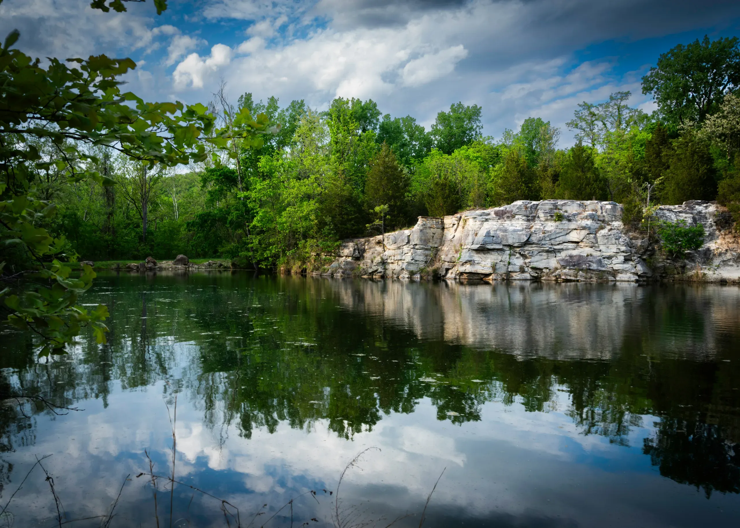 Klondike Park, Augusta, Missouri. Lake reflection next to a bluff with a blue sky and white clouds