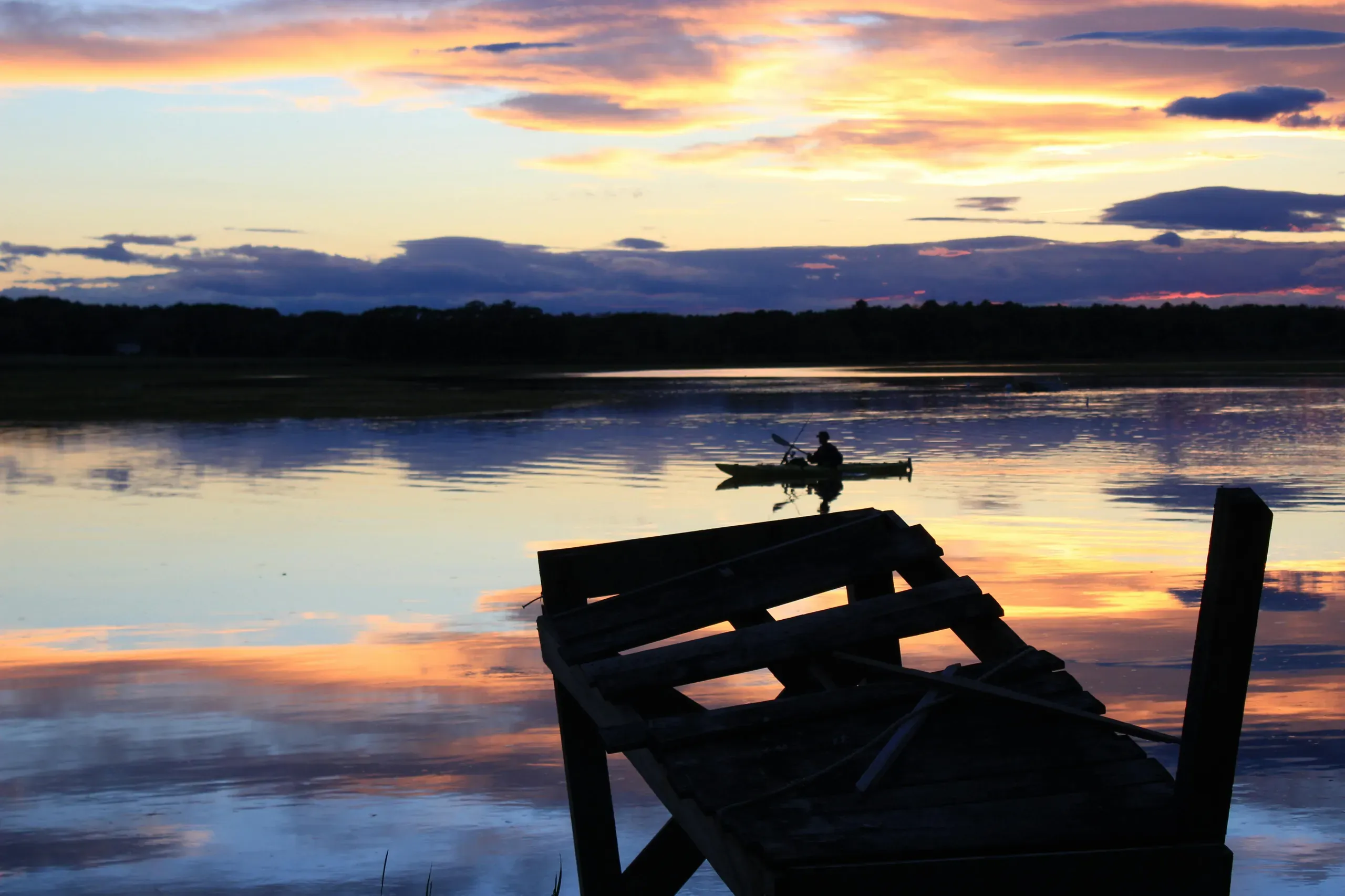 Peaceful scene of a person paddling a small boat as he fishes near the shore in Scarborough, Maine.