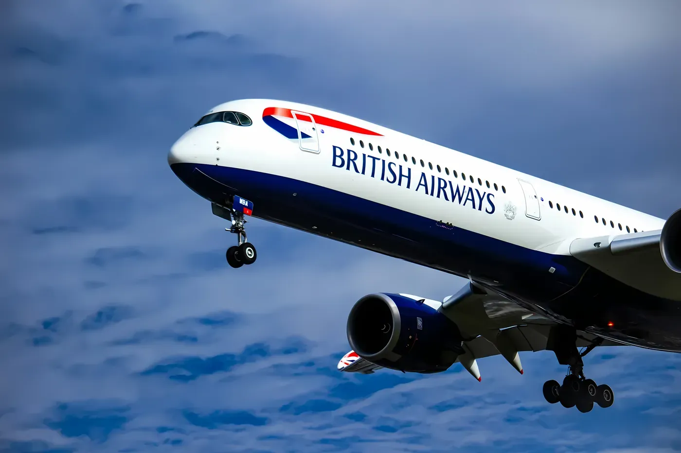 A British Airways aircraft on approach with landing gear down against a blue sky