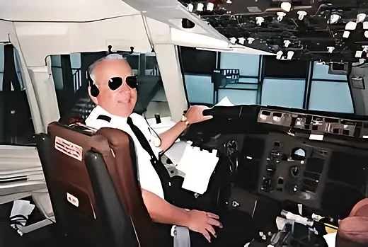 Captain Russ Wittenberg seated in a commercial airliner cockpit, wearing aviator sunglasses and a pilot's uniform shirt with epaulettes