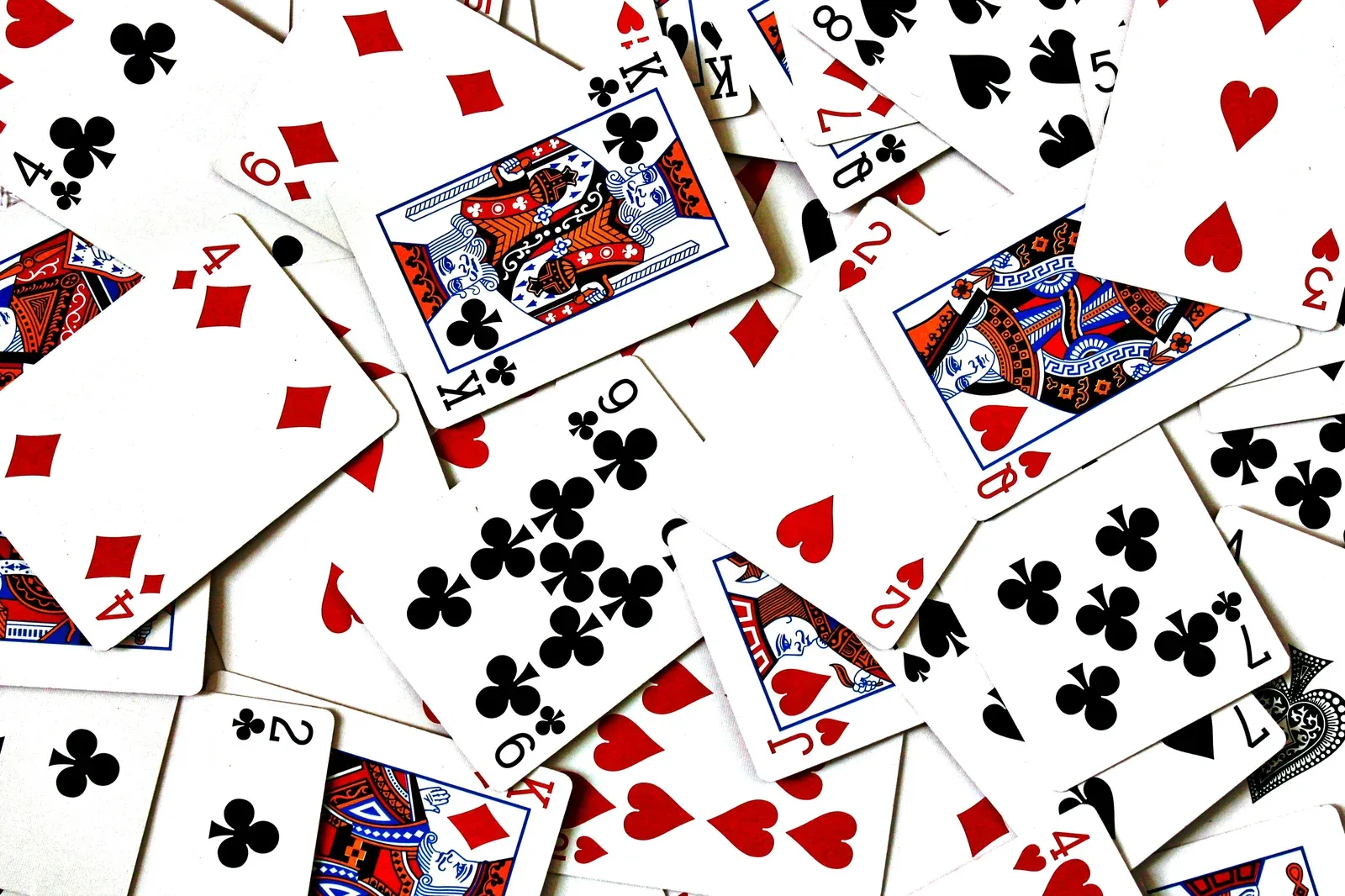 A scattered pile of playing cards face up, showing a jumble of suits and values