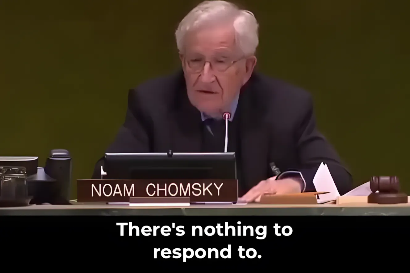 Noam Chomsky speaking at a UN panel with his name placard, subtitled 'There's nothing to respond to.'