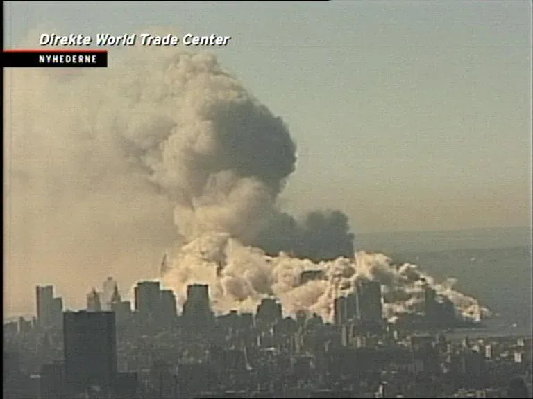 Closer aerial view of WTC dust cloud rising over lower Manhattan, Danish Nyhederne TV overlay reading Direkte World Trade Center