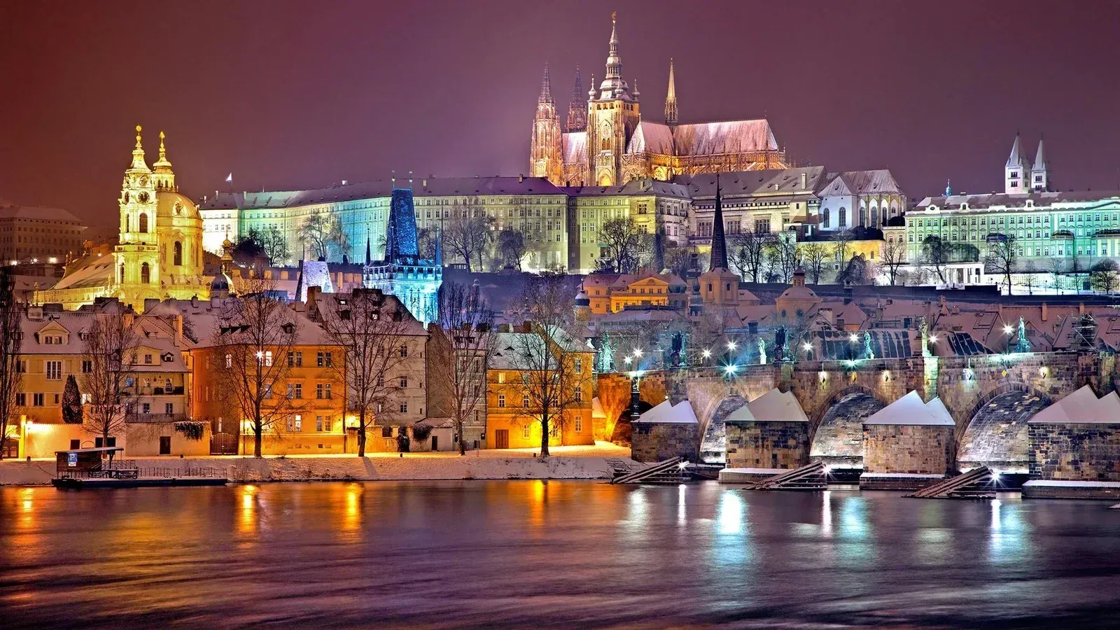 Prague Castle and St Vitus Cathedral illuminated at night above the Charles Bridge and the Vltava River