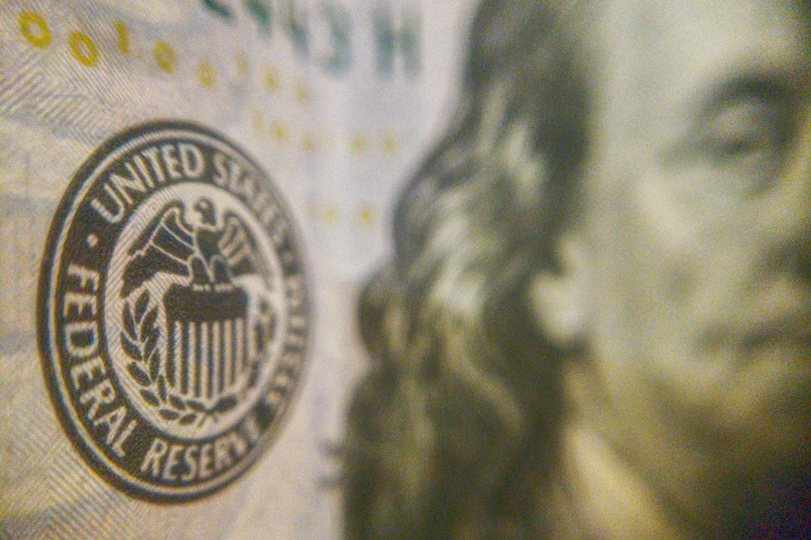 Close-up of a US dollar bill showing the Federal Reserve seal with Benjamin Franklin's portrait blurred in the background