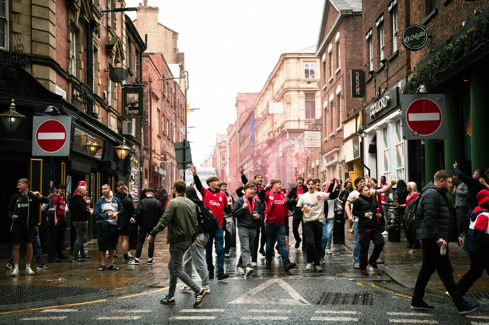 Liverpool FC fans celebrating on the streets of Liverpool with red flares and scarves