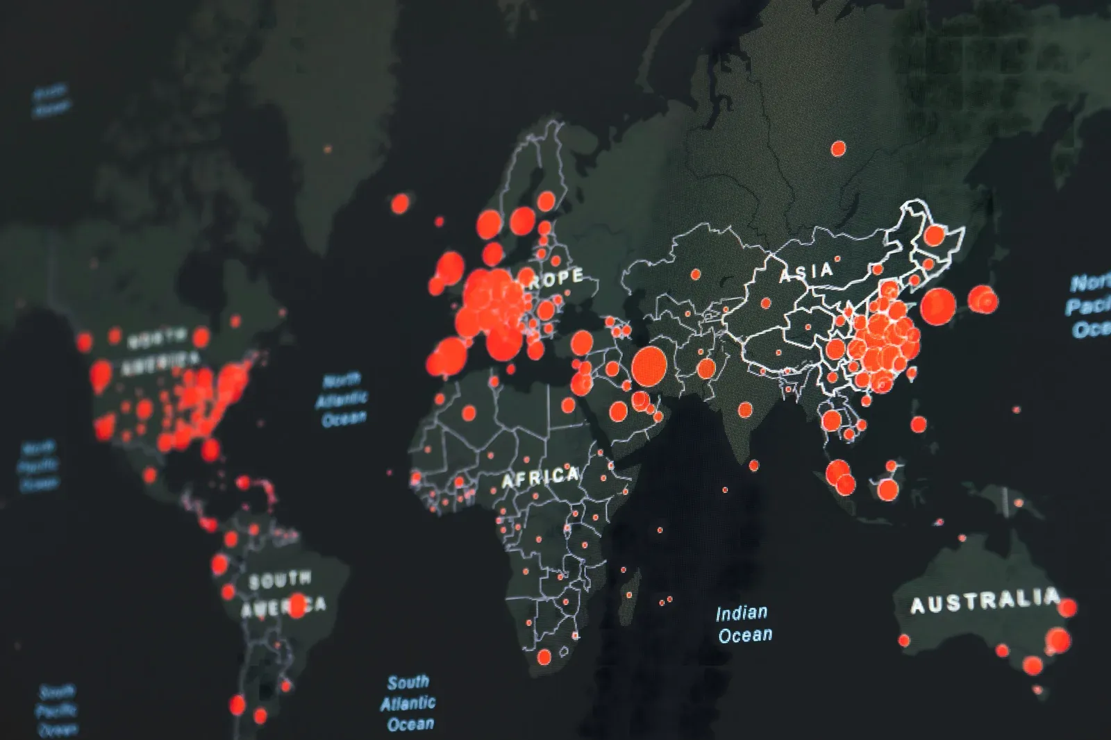 Dark world map with red circles showing COVID-19 case concentrations by region