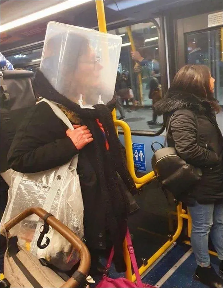 Photo of person on public transport wearing a clear plastic storage container on their head as an improvised face shield