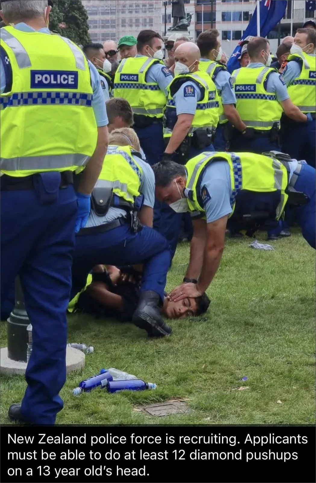 Photo of New Zealand police restraining protester face-down on the ground during anti-mandate protest. Caption: NZ police recruiting, applicants must be able to do at least 12 diamond pushups on a 13 year old's head