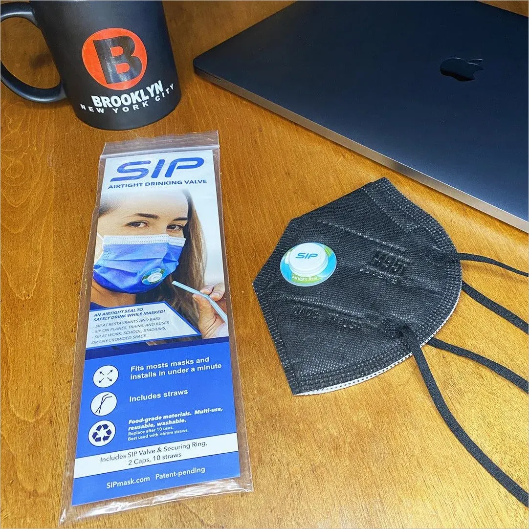 Product photo on desk showing SIP mask packaging with straw hole feature next to a black KN95 mask, laptop, and Brooklyn coffee cup
