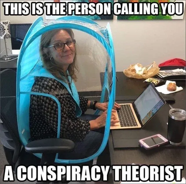 Meme captioned THIS IS THE PERSON CALLING YOU A CONSPIRACY THEORIST showing woman sitting at desk using laptop while enclosed in a blue pop-up personal pod tent