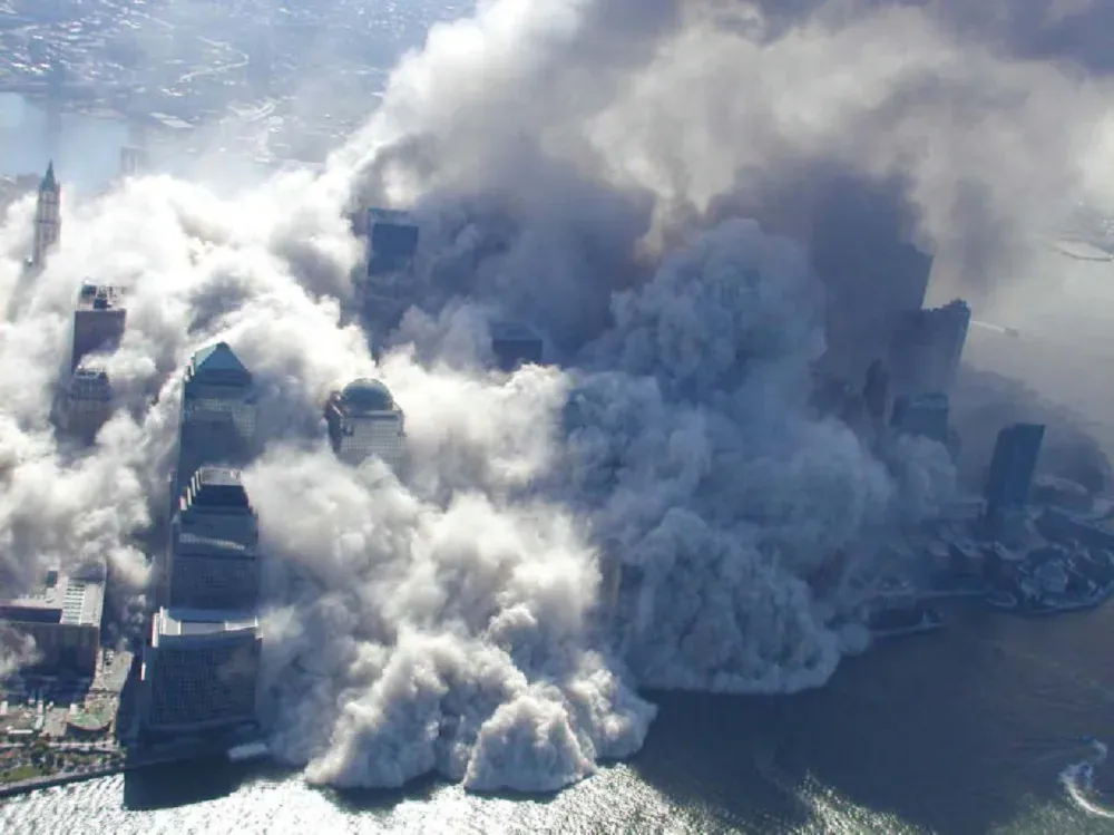 Aerial photograph of lower Manhattan engulfed in thick white dust and debris clouds from the WTC collapse, buildings partially visible through the dust