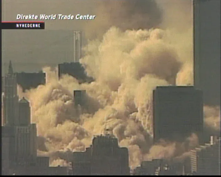 Danish Nyhederne TV screenshot showing orange-brown dust cloud expanding through lower Manhattan after a tower collapse, buildings partially obscured, Direkte World Trade Center overlay