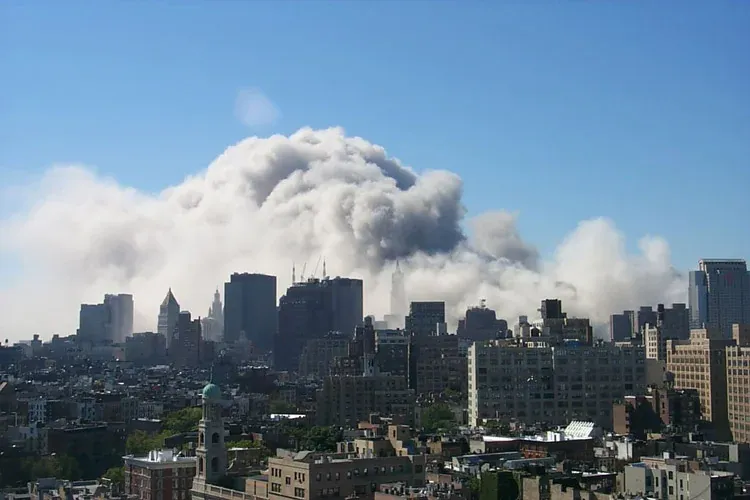 Distant view of WTC dust cloud spreading horizontally over the Manhattan skyline, larger and more dispersed than earlier moments