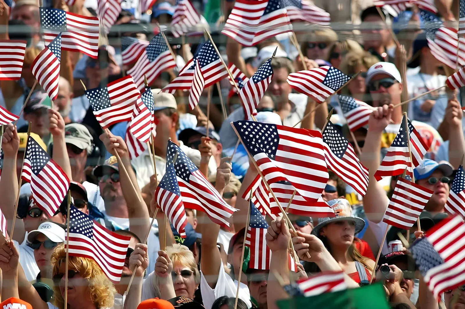 A crowd of spectators waving small American flags at a NASCAR event