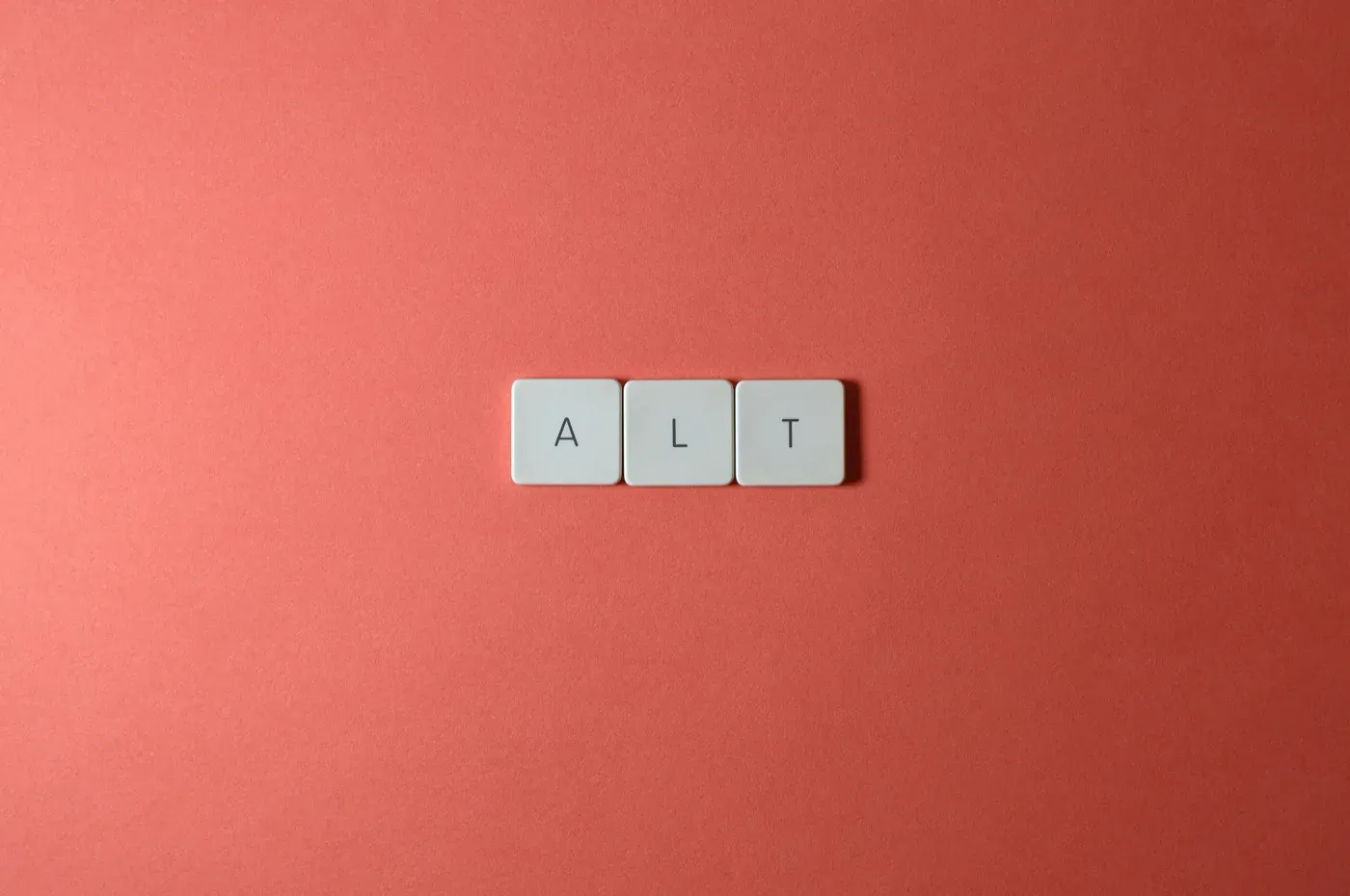 Three keyboard keycaps spelling ALT on a coral pink background