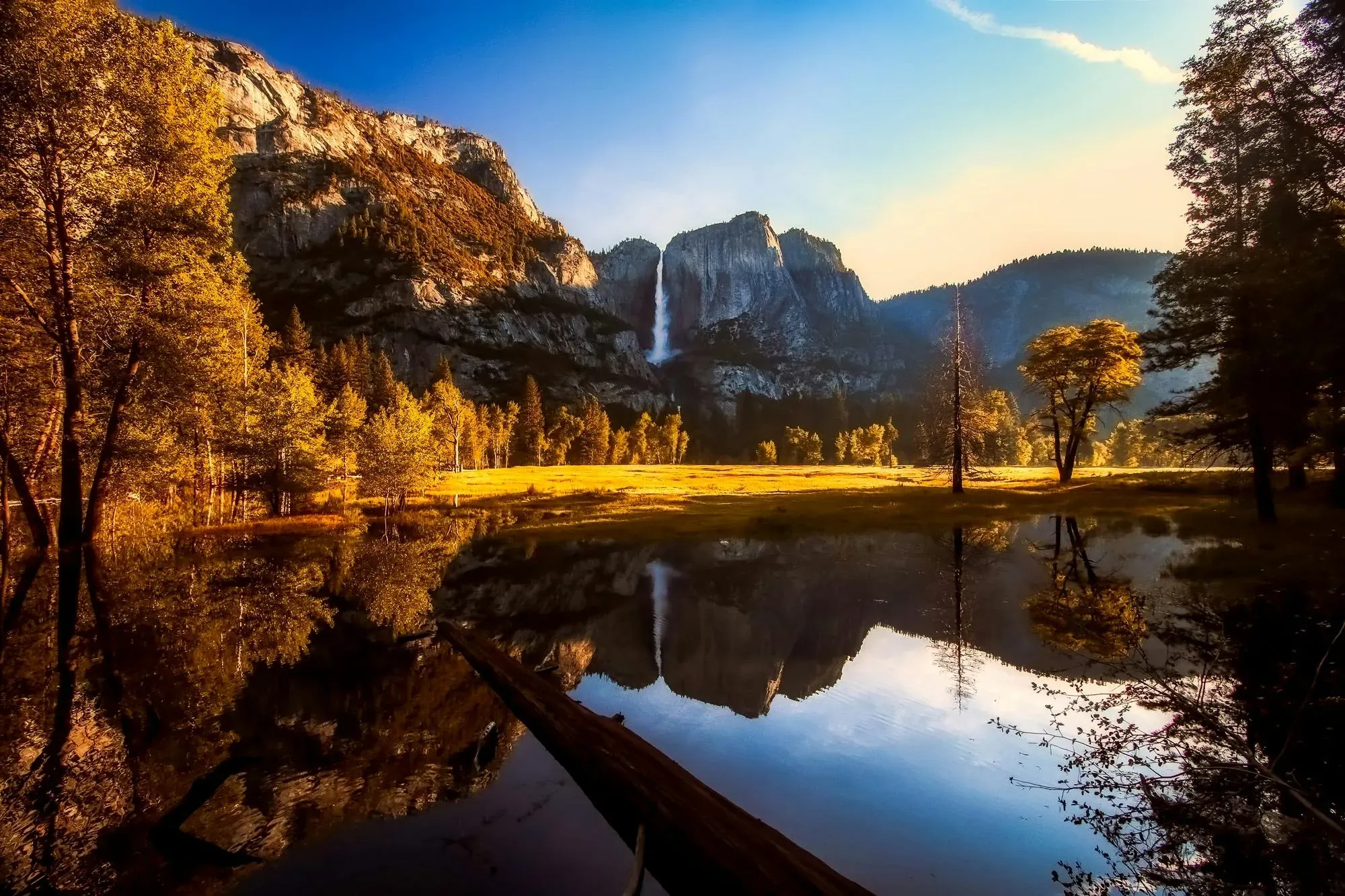 Yosemite Valley at golden hour with Yosemite Falls, granite cliffs and trees reflected in the Merced River
