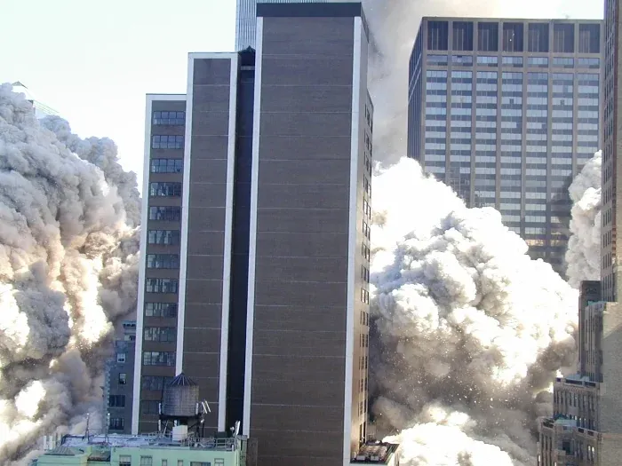 Street-level view of a massive white dust cloud surging around tall buildings in lower Manhattan like a pyroclastic flow, rooftop water tank visible in foreground