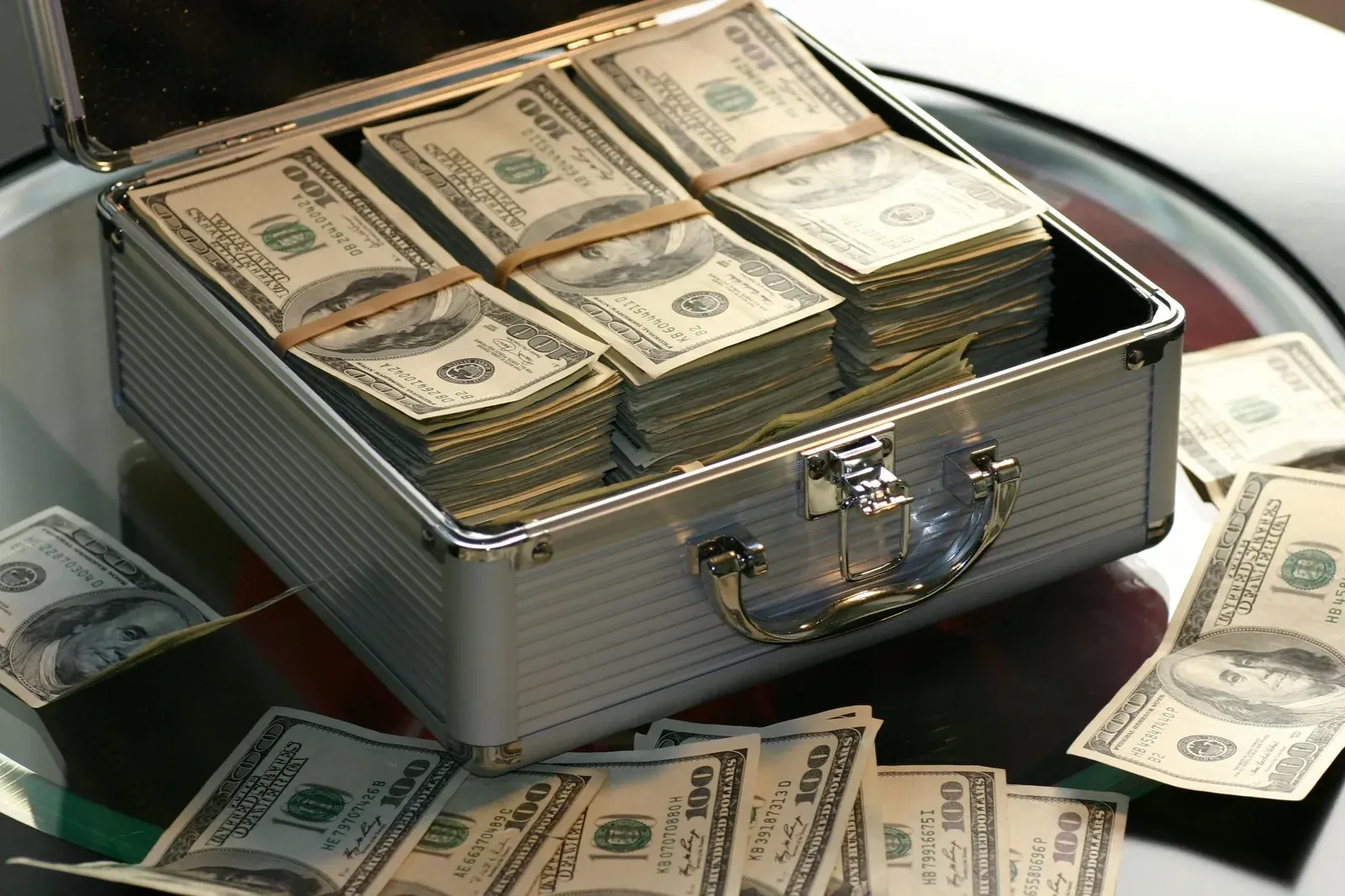 A metal briefcase stuffed with bundles of hundred-dollar bills, more notes scattered around it