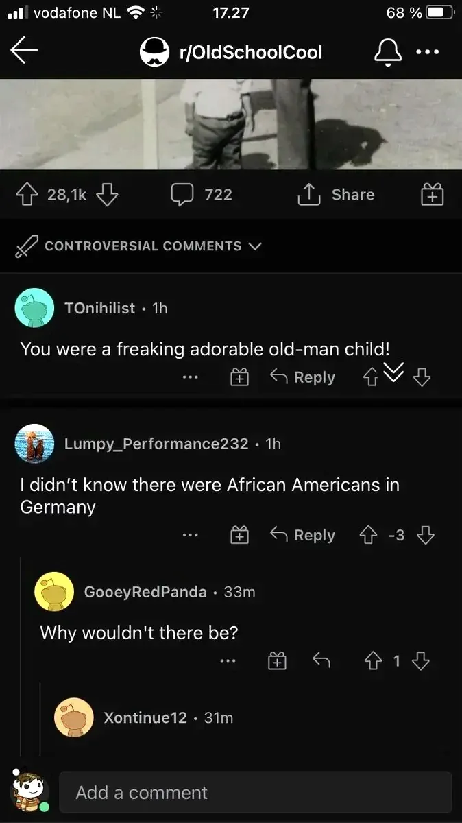 Reddit mobile screenshot (vodafone NL). r/OldSchoolCool post with partial black and white photo of a child. Sorted by CONTROVERSIAL COMMENTS. TOnihilist (1h): "You were a freaking adorable old-man child!" Lumpy_Performance232 (1h, -3 votes): "I didn't know there were African Americans in Germany". GooeyRedPanda (33m): "Why wouldn't there be?"