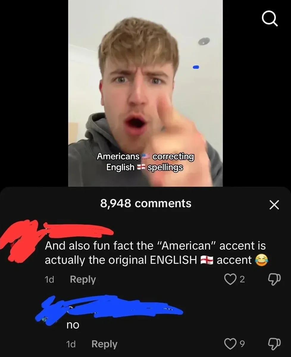 TikTok screenshot. Video showing young man with blond hair in grey hoodie, shocked expression, hand reaching toward camera. Caption: "Americans correcting English spellings" with US and England flag emojis. First comment (username redacted, 1d): "And also fun fact the 'American' accent is actually the original ENGLISH accent" with England flag and laughing-crying emojis. Reply (username redacted, 1d): "no"
