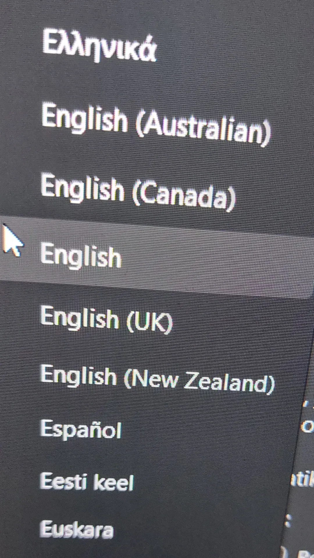 Photo of a computer screen showing a language selection dropdown menu. Options listed:????????, English (Australian), English (Canada), English (highlighted/selected with mouse cursor), English (UK), English (New Zealand), Espanol, Eesti keel, Euskara. Plain "English" is listed separately from regional variants, implying American English is the default