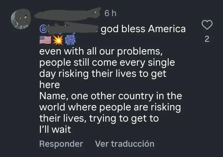 TikTok/Instagram comment with Spanish-language interface ("Responder", "Ver traduccion"). Username redacted, 6h. Profile text: "god bless America" with US flag, star, and fireworks emojis. Text: "even with all our problems, people still come every single day risking their lives to get here Name, one other country in the world where people are risking their lives, trying to get to I'll wait"