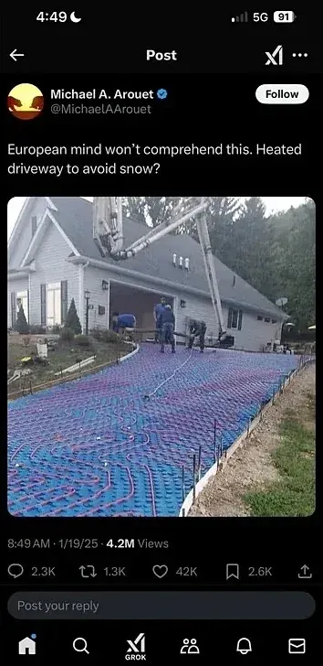 X/Twitter post (mobile screenshot, 4:49, 5G). Michael A. Arouet (verified) @MichaelAArouet (Follow button). Text: "European mind won't comprehend this. Heated driveway to avoid snow?" Photo showing workers installing blue radiant heating pipes/panels across a large driveway in front of a white house. 8:49 AM, 1/19/25.