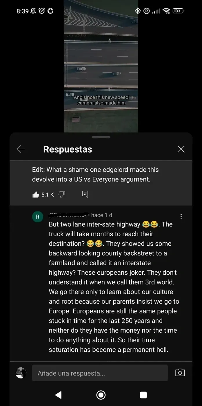YouTube comment thread with Spanish-language interface ("Respuestas", "Anade una respuesta..."). Mobile. Video thumbnail showing aerial view of highway with text "And since this new speed camera also made him". Parent comment (highlighted): "Edit: What a shame one edgelord made this devolve into a US vs Everyone argument." Reply (green hace 1 d): "But two lane inter-sate highway" with laughing emojis. "The truck will take months to reach their destination?" with laughing emojis. "They showed us some backward looking county backstreet to a farmland and called it an interstate highway? These europeans joker. They don't understand it when we call them 3rd world. We go there only to learn about our culture and root because our parents insist we go to Europe. Europeans are still the same people stuck in time for the last 250 years and neither do they have the money nor the time to do anything about it. So their time saturation has become a permanent hell."