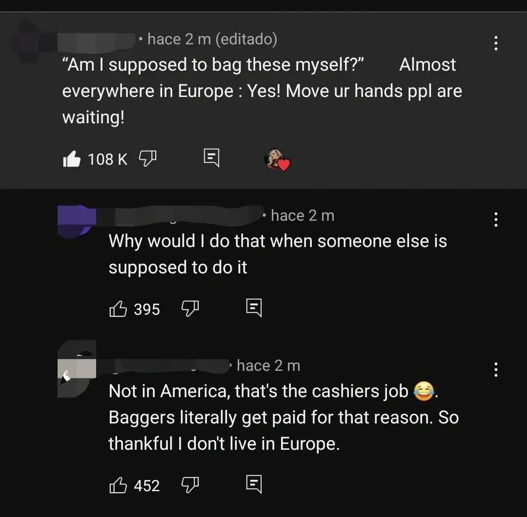 YouTube comment thread with Spanish-language interface ("hace 2 m", "editado"). First (username obscured, hace 2 m, editado, heart from creator): "Am I supposed to bag these myself?" Almost everywhere in Europe: Yes! Move ur hands ppl are waiting!" Second (hace 2 m): "Why would I do that when someone else is supposed to do it" Third (hace 2 m): "Not in America, that's the cashiers job" laughing emoji. "Baggers literally get paid for that reason. So thankful I don't live in Europe."
