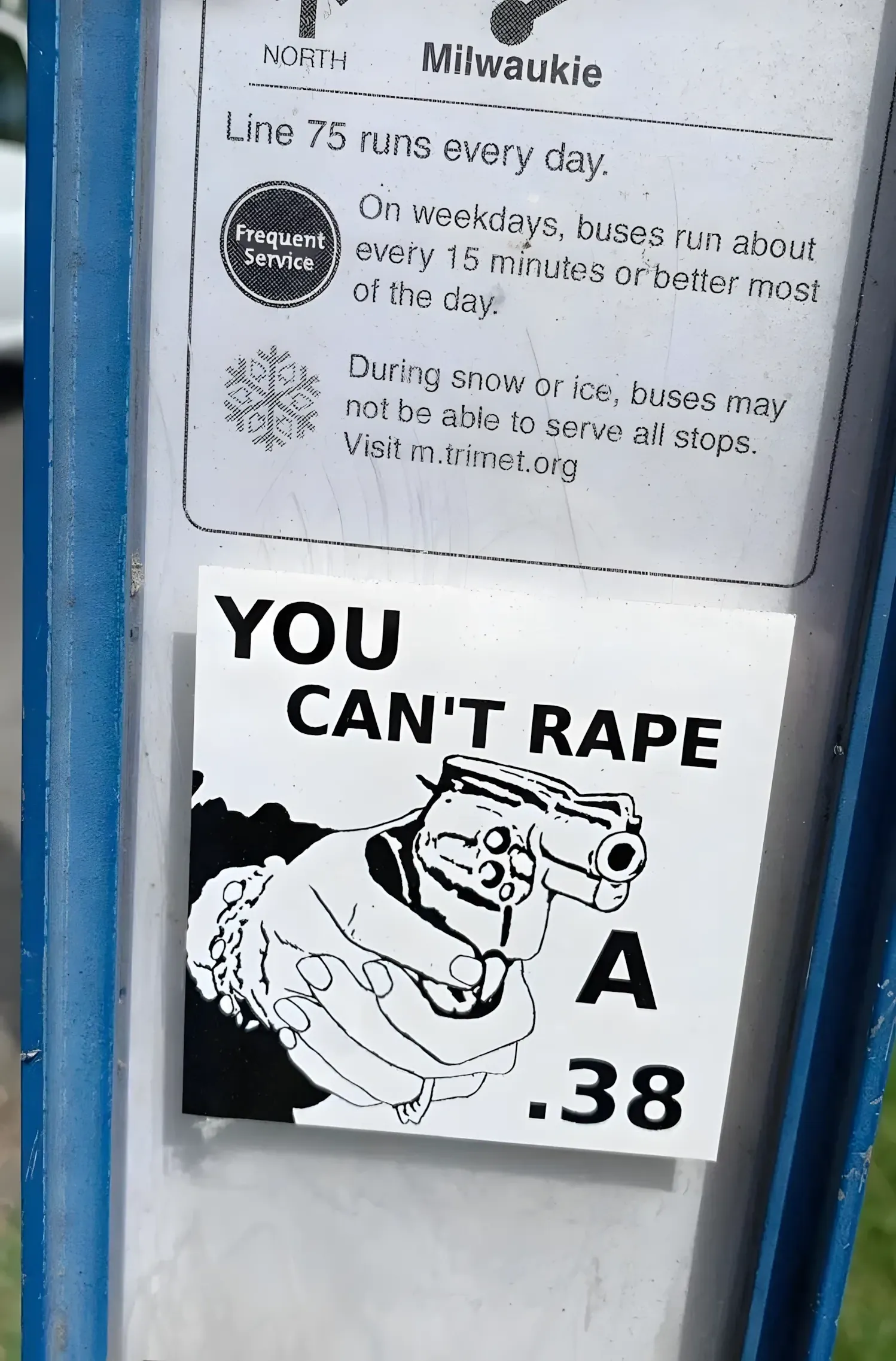 Photo of a bus stop pole. Top half shows a TriMet transit sign for North Milwaukie (Line 75, Frequent Service, runs every day, every 15 minutes on weekdays). Below it, a white sticker with a drawing of hands holding a revolver and text "YOU CAN'T RAPE A .38"