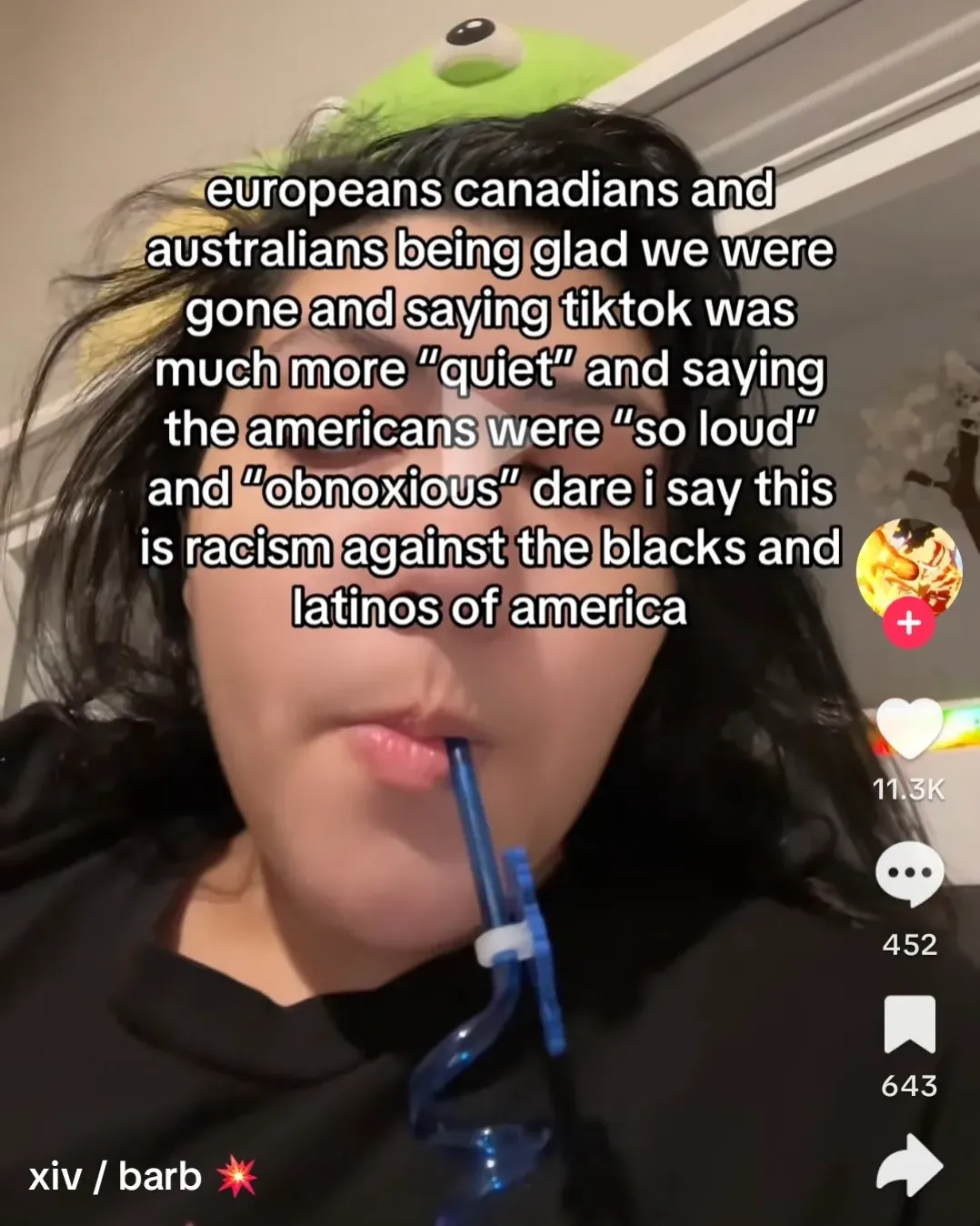 TikTok screenshot. Video of a person with a green frog plush on their head drinking from a blue cup. Text overlay: "europeans canadians and australians being glad we were gone and saying tiktok was much more 'quiet' and saying the americans were 'so loud' and 'obnoxious' dare i say this is racism against the blacks and latinos of america". Username: xiv / barb