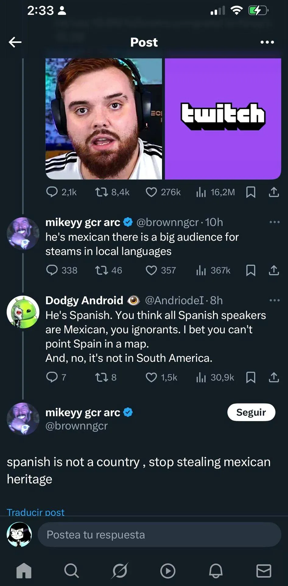 Twitter/X thread. Post showing a Twitch streamer (bearded man with headphones) next to Twitch logo. mikeyy gcr arc (@brownngcr, verified, 10h): "he's mexican there is a big audience for steams in local languages". Dodgy Android (@AndriodeI, 8h): "He's Spanish. You think all Spanish speakers are Mexican, you ignorants. I bet you can't point Spain in a map. And, no, it's not in South America." mikeyy gcr arc: "spanish is not a country, stop stealing mexican heritage". Spanish-language interface
