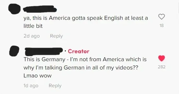 TikTok comment thread. First comment (username redacted, 2d ago): "ya, this is America gotta speak English at least a little bit". Reply (Creator tag, 1d ago): "This is Germany - I'm not from America which is why I'm talking German in all of my videos?? Lmao wow"