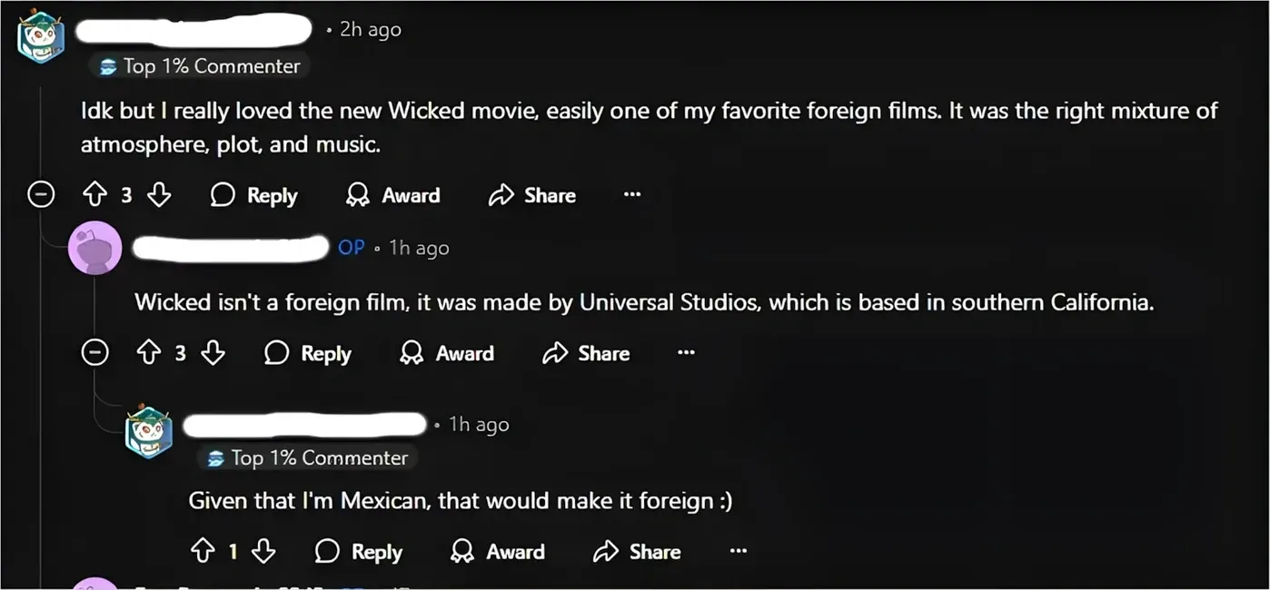 Reddit comment thread. First commenter (username whited out, Top 1% Commenter badge, 2h ago): "Idk but I really loved the new Wicked movie, easily one of my favorite foreign films. It was the right mixture of atmosphere, plot, and music." OP reply (1h ago): "Wicked isn't a foreign film, it was made by Universal Studios, which is based in southern California." Reply (username whited out, Top 1% Commenter badge, 1h ago): "Given that I'm Mexican, that would make it foreign :)"