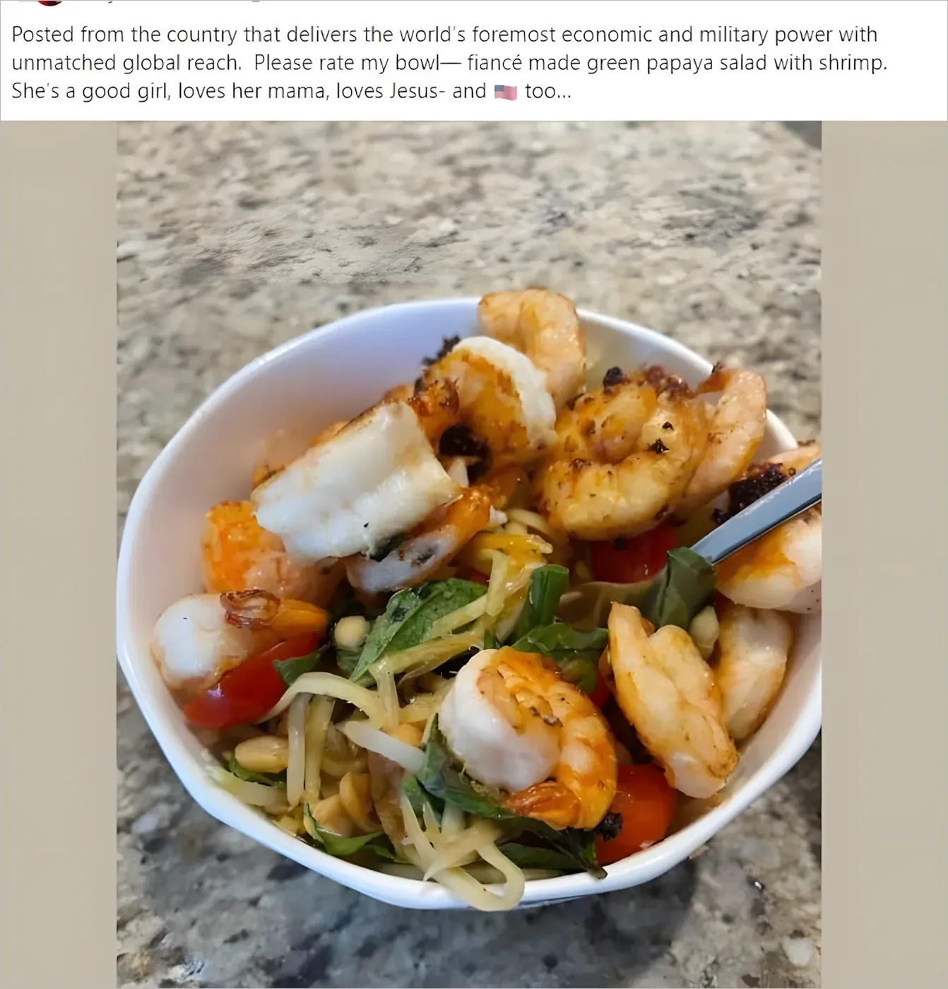 Social media post (username scribbled). Text: "Posted from the country that delivers the world's foremost economic and military power with unmatched global reach. Please rate my bowl - fiance made green papaya salad with shrimp. She's a good girl, loves her mama, loves Jesus- and [American flag emoji] too..." Photo shows a white bowl of green papaya salad with grilled shrimp, cherry tomatoes, herbs and peanuts on a granite countertop.
