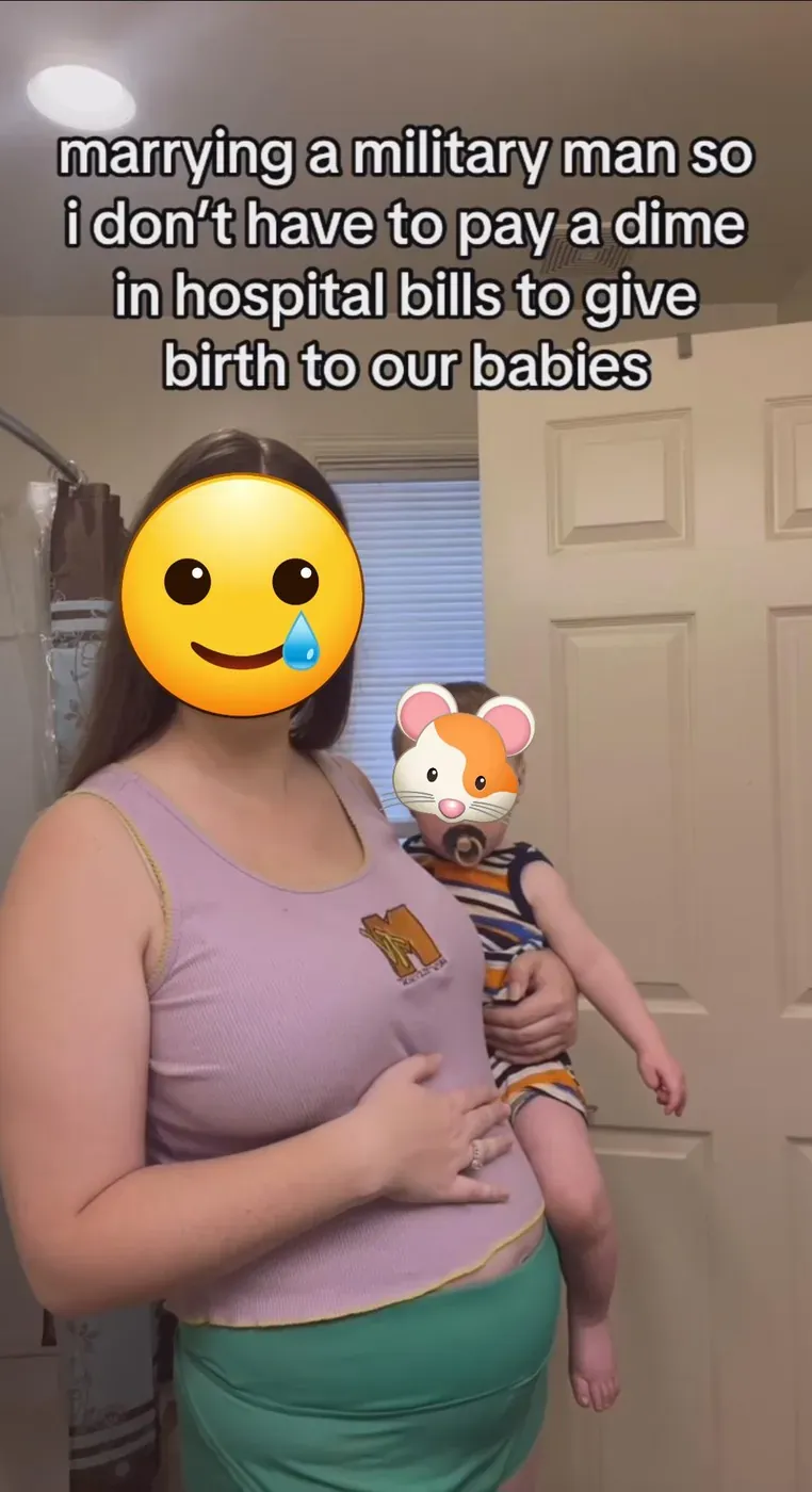 TikTok video screenshot. A pregnant woman in a lavender tank top holding a toddler, standing in a bathroom. Her face is covered with a smiling-with-tear emoji, the child's face with a hamster emoji. Text overlay: "marrying a military man so i don't have to pay a dime in hospital bills to give birth to our babies"