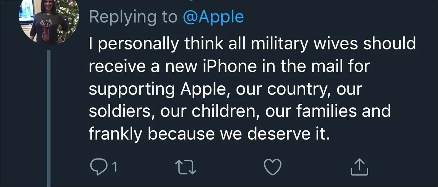Twitter/X reply. Replying to @Apple. Profile pic shows a woman in a patriotic t-shirt by a Christmas tree. Text: "I personally think all military wives should receive a new iPhone in the mail for supporting Apple, our country, our soldiers, our children, our families and frankly because we deserve it.", no retweets or likes.