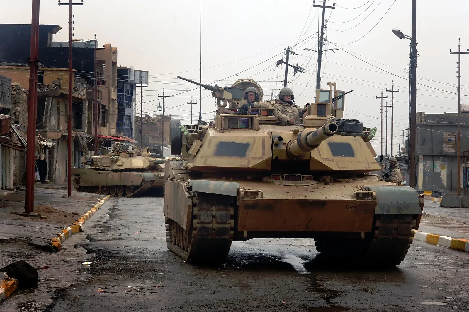 Two US Army M1A2 Abrams tanks rolling through a damaged street in Tall Afar, Iraq