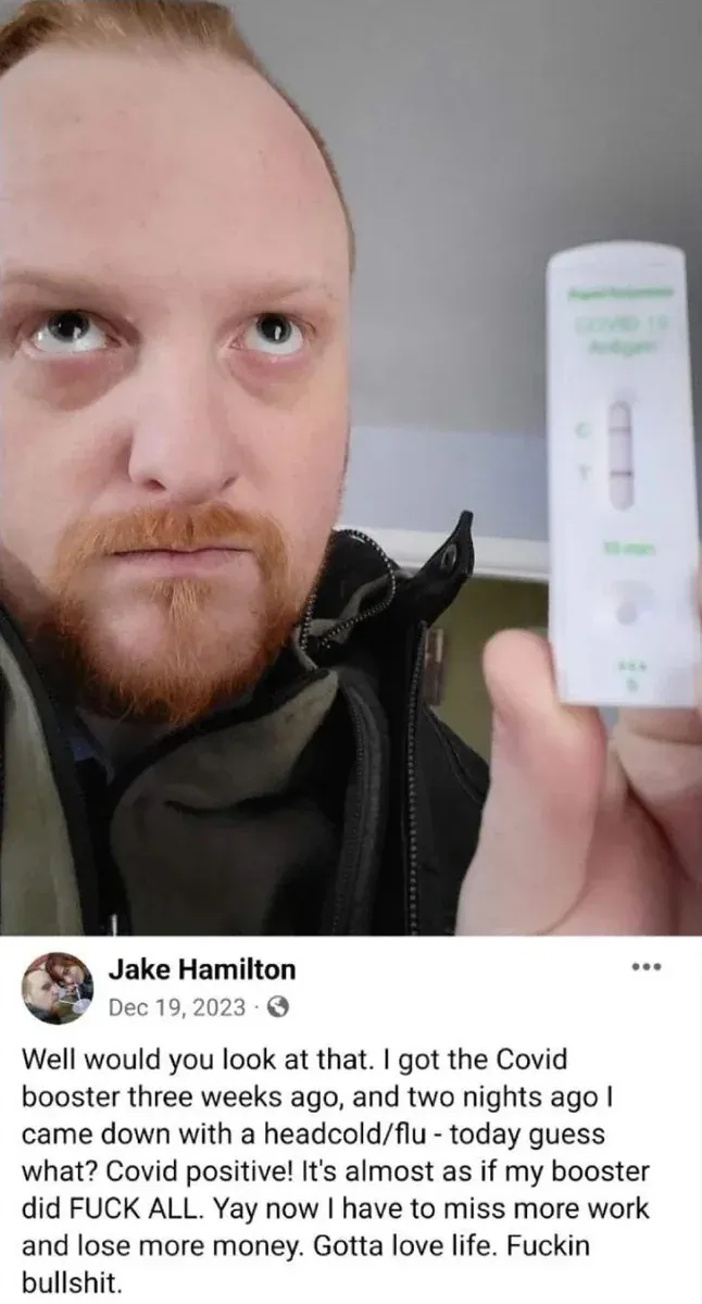 Jake Hamilton Facebook post (Dec 19 2023) - selfie holding positive COVID test. Got the Covid booster three weeks ago, came down with headcold/flu two nights ago, today Covid positive. It's almost as if my booster did FUCK ALL. Now has to miss more work and lose more money